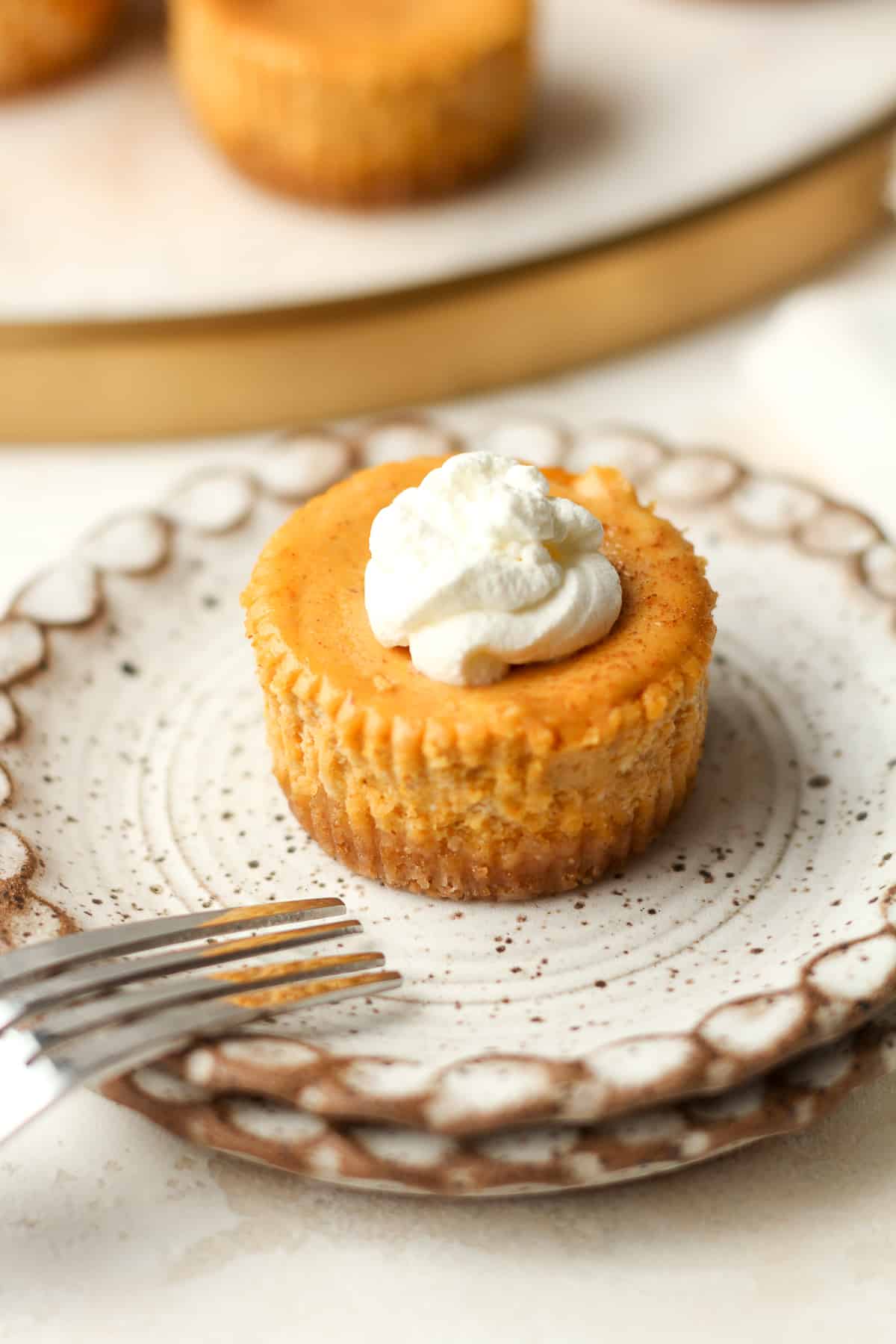 A mini pumpkin cheesecake on a plate with a fork.