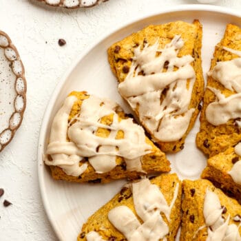 A plate of iced pumpkin chocolate chip scones.