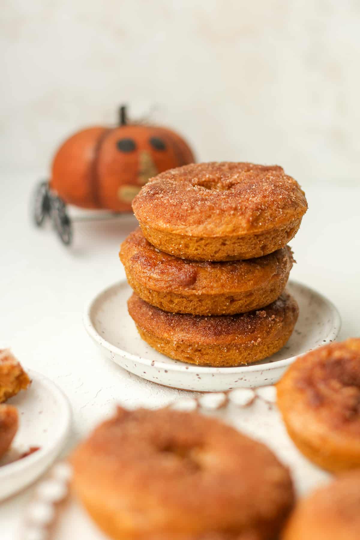 A small plate with three pumpkin donuts with cinnamon sugar topping.