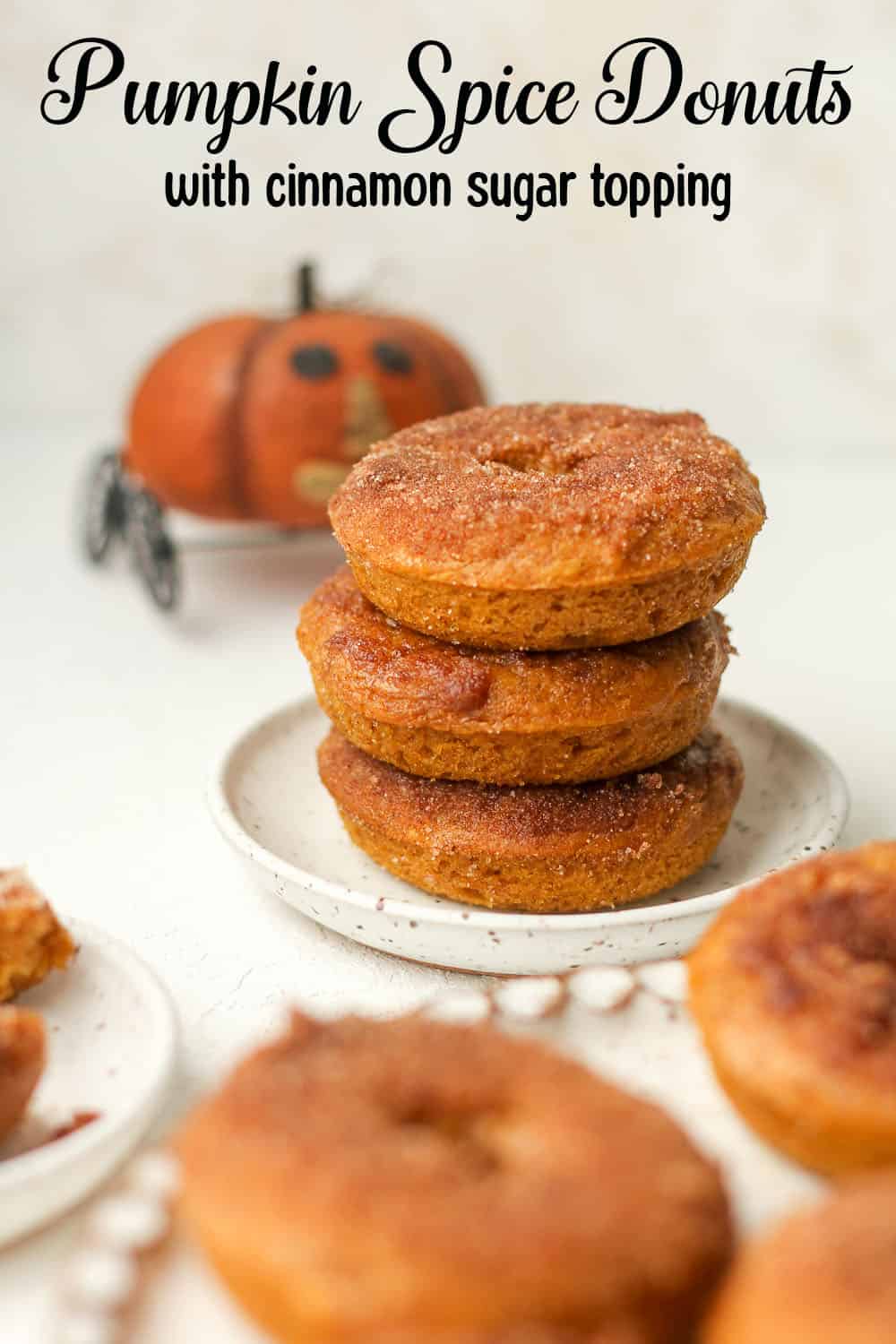 A small plate with three stacked pumpkin donuts with cinnamon sugar topping.