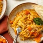 A bowl of creamy pasta with butternut squash and a fork.