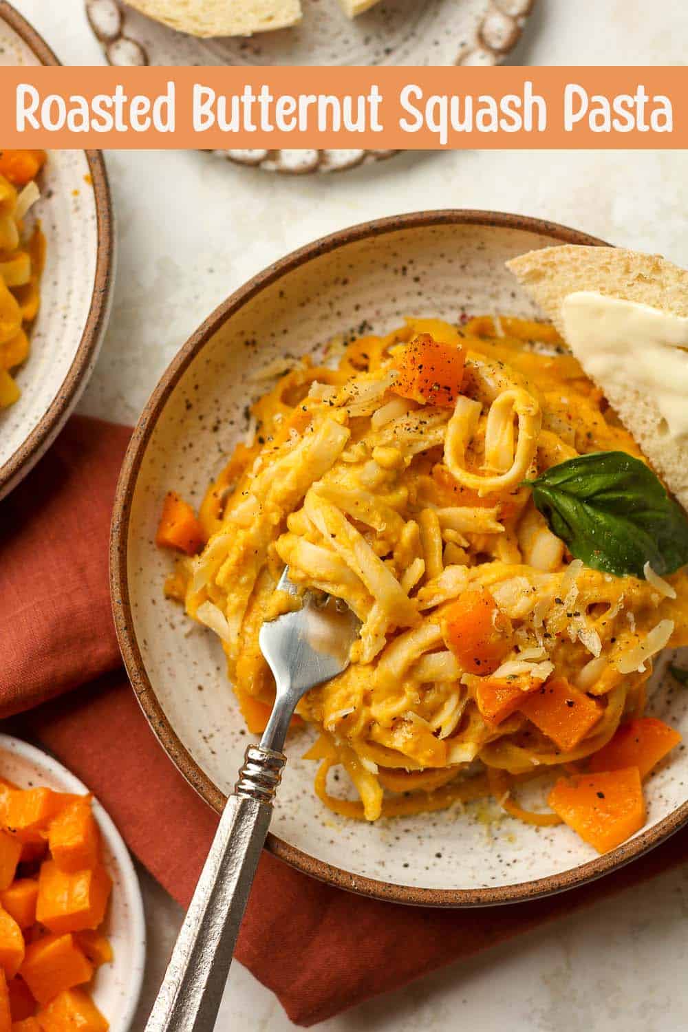 A bowl of creamy pasta with butternut squash and a fork.