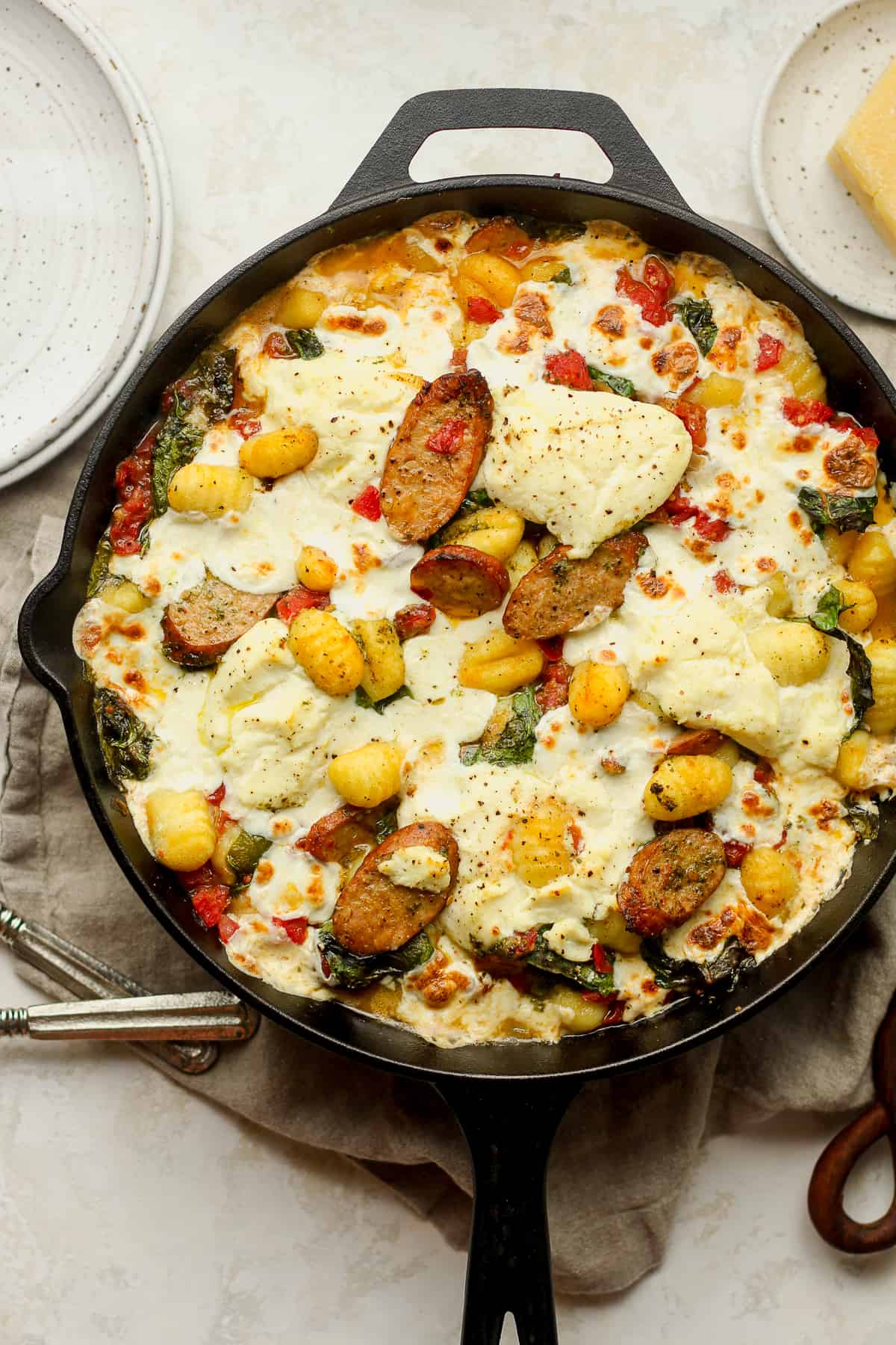 A skillet of cheesy sausage and gnocchi with veggies.