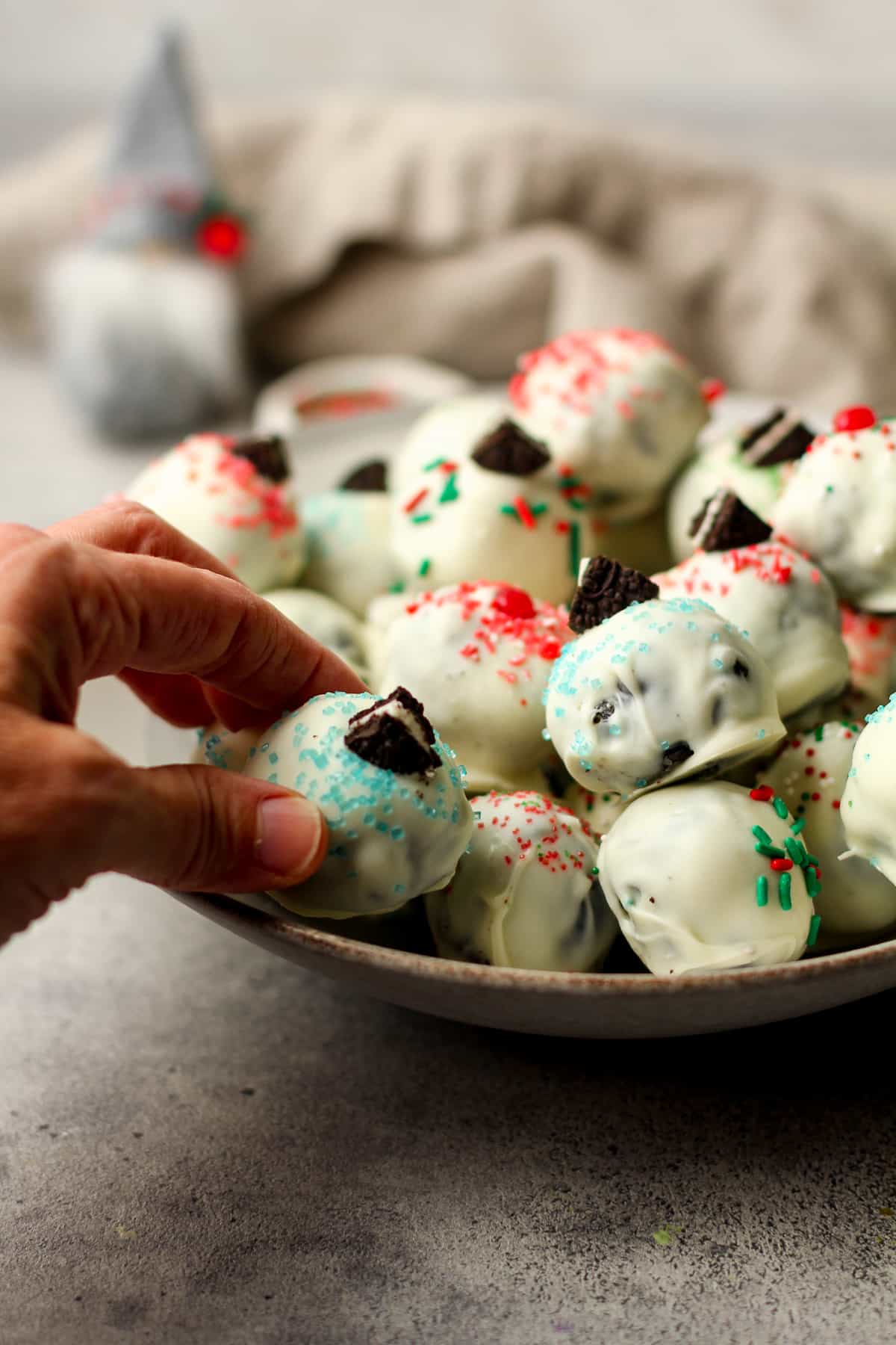 Side view of a bowl of Oreo truffles and my hand reaching for one.