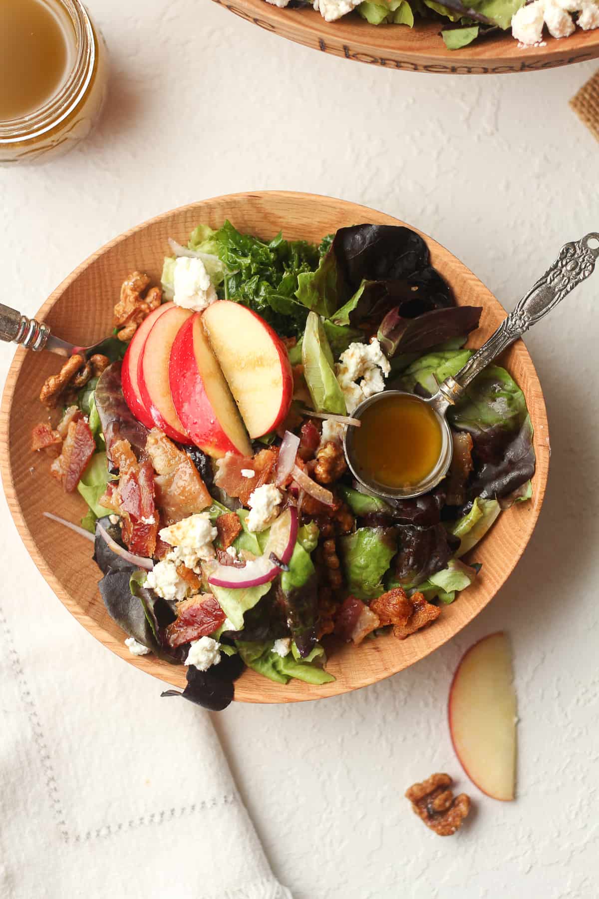 A wooden serving bowl of the Fall harvest salad with the dressing over top.