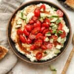 A black bowl of Greek Feta Dip with marinated tomatoes.
