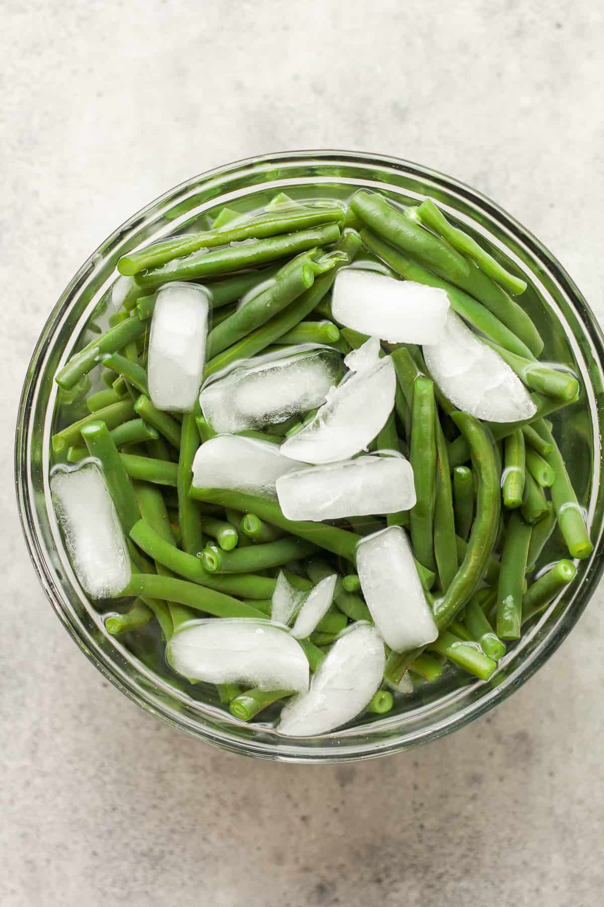 A bowl of the green beans in ice water.