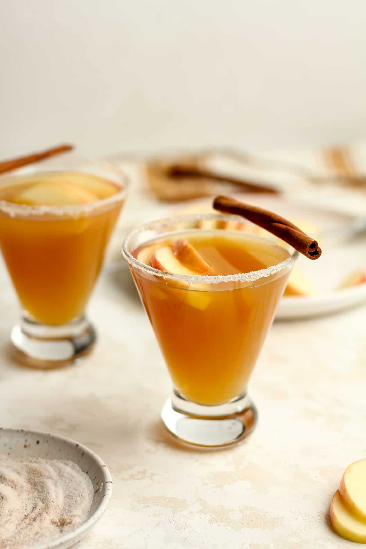 Side view of two apple cider martinis with cinnamon sticks.