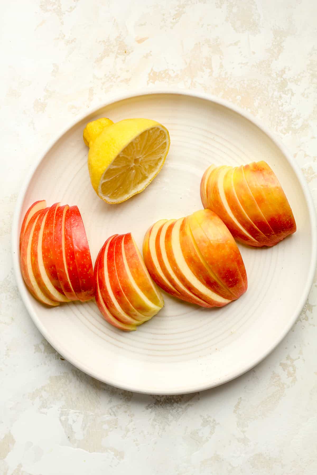 A plate of apples slices with a half lemon.
