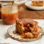 Side view of a piece of apple cake with caramel sauce, and a jar of caramel in the background.