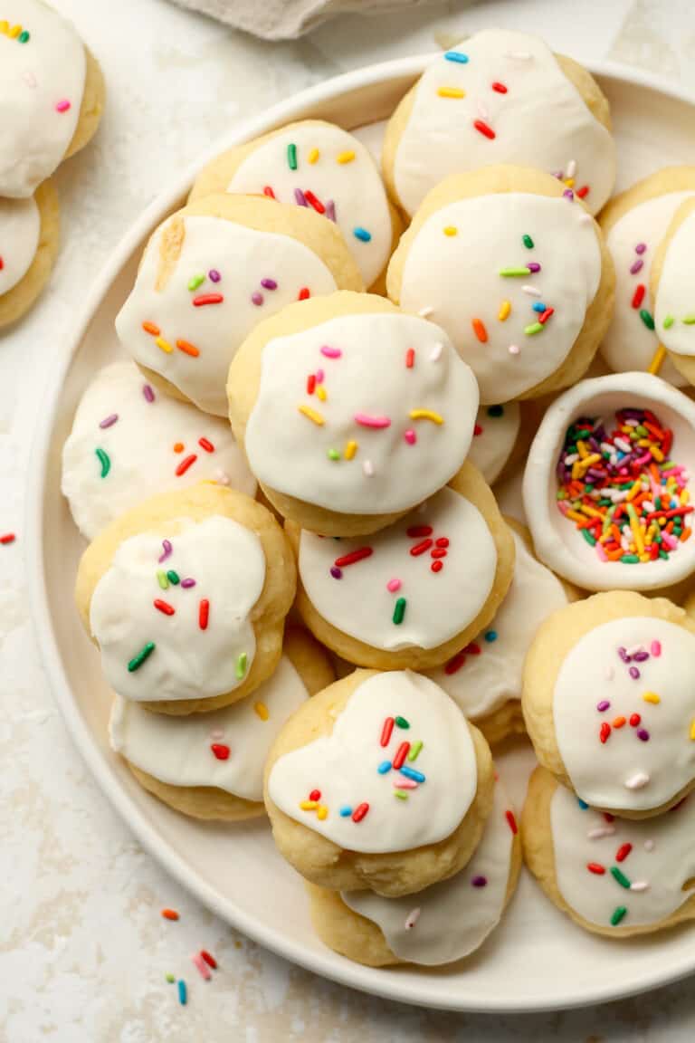 A closeup on a large plate of lemon ricotta cookies with sprinkles.