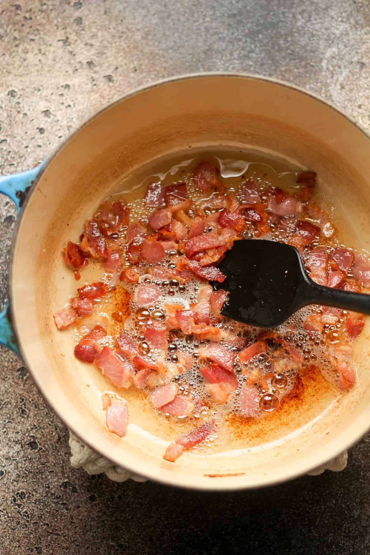 A pot of sautéed bacon pieces.