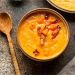 A bowl of butternut squash soup with bacon.