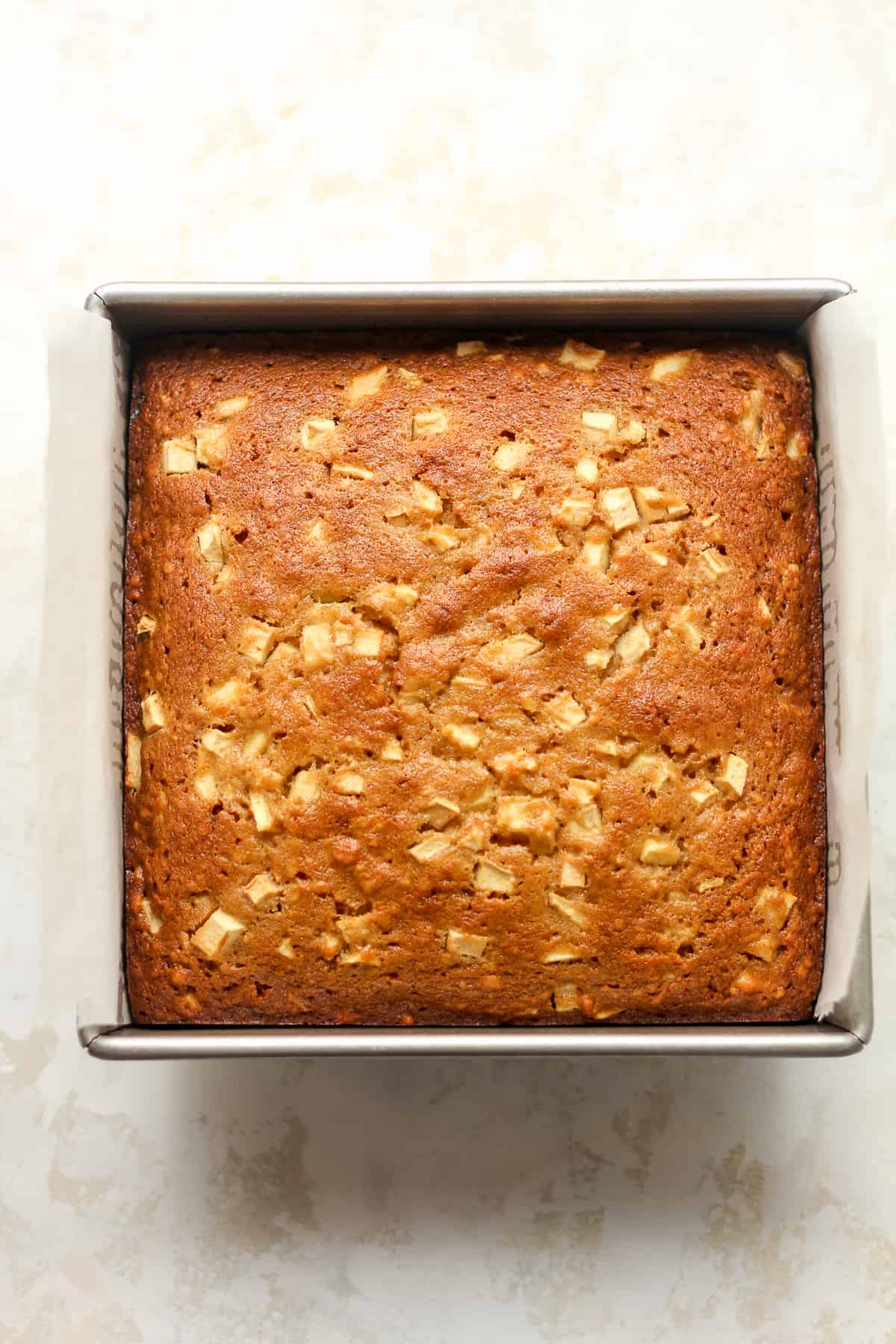 A square cake pan with a baked applesauce cake.