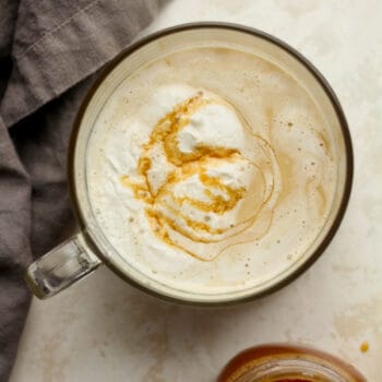 A closeup of a large glass mug of caramel latte.