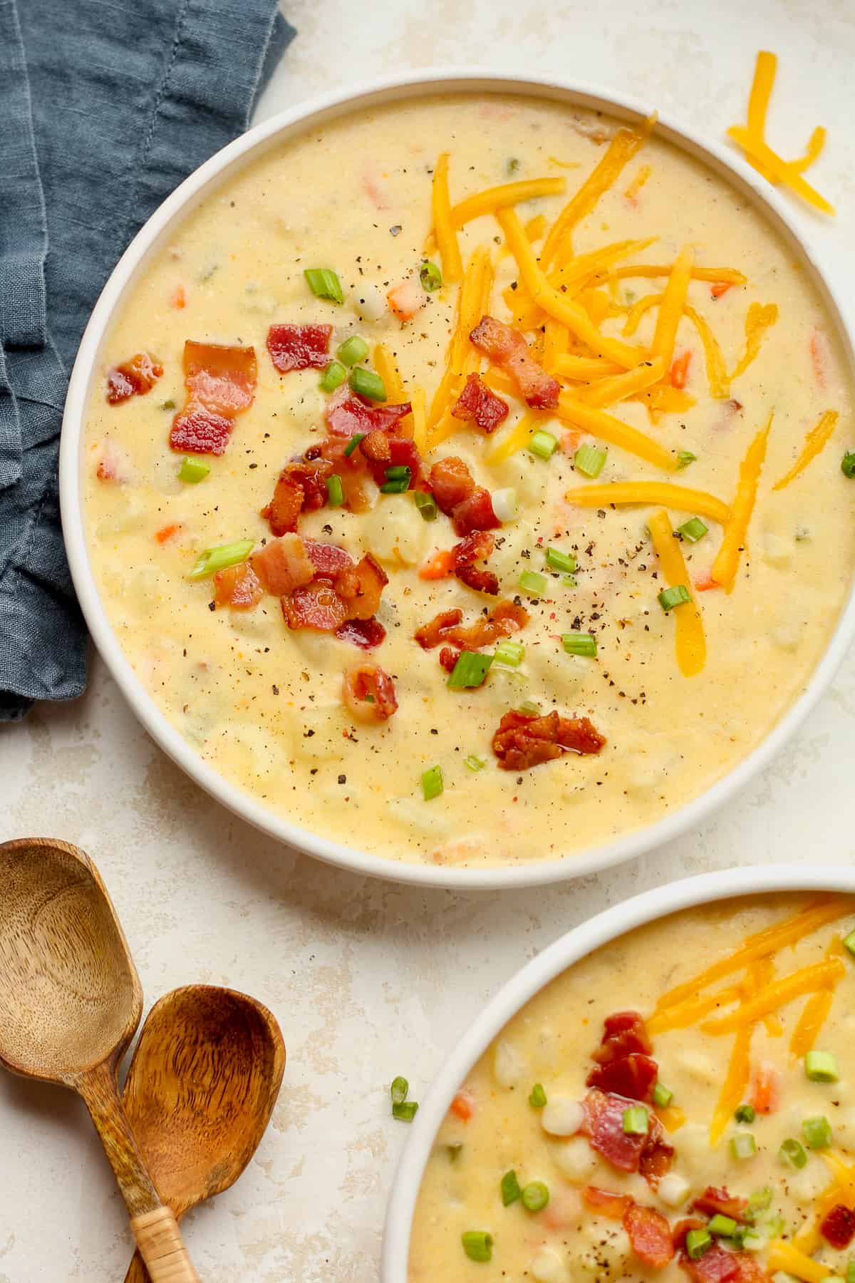 A shallow bowl of potato soup with bacon and cheese on top.