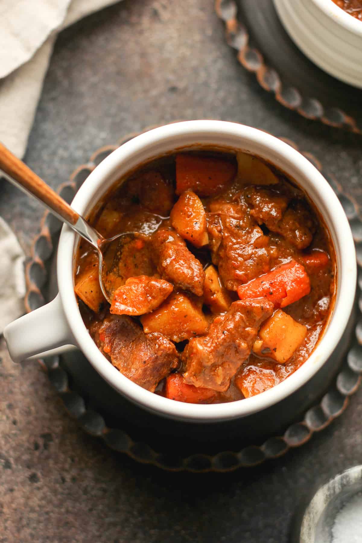 A mug of curry beef stew with carrots and potatoes.