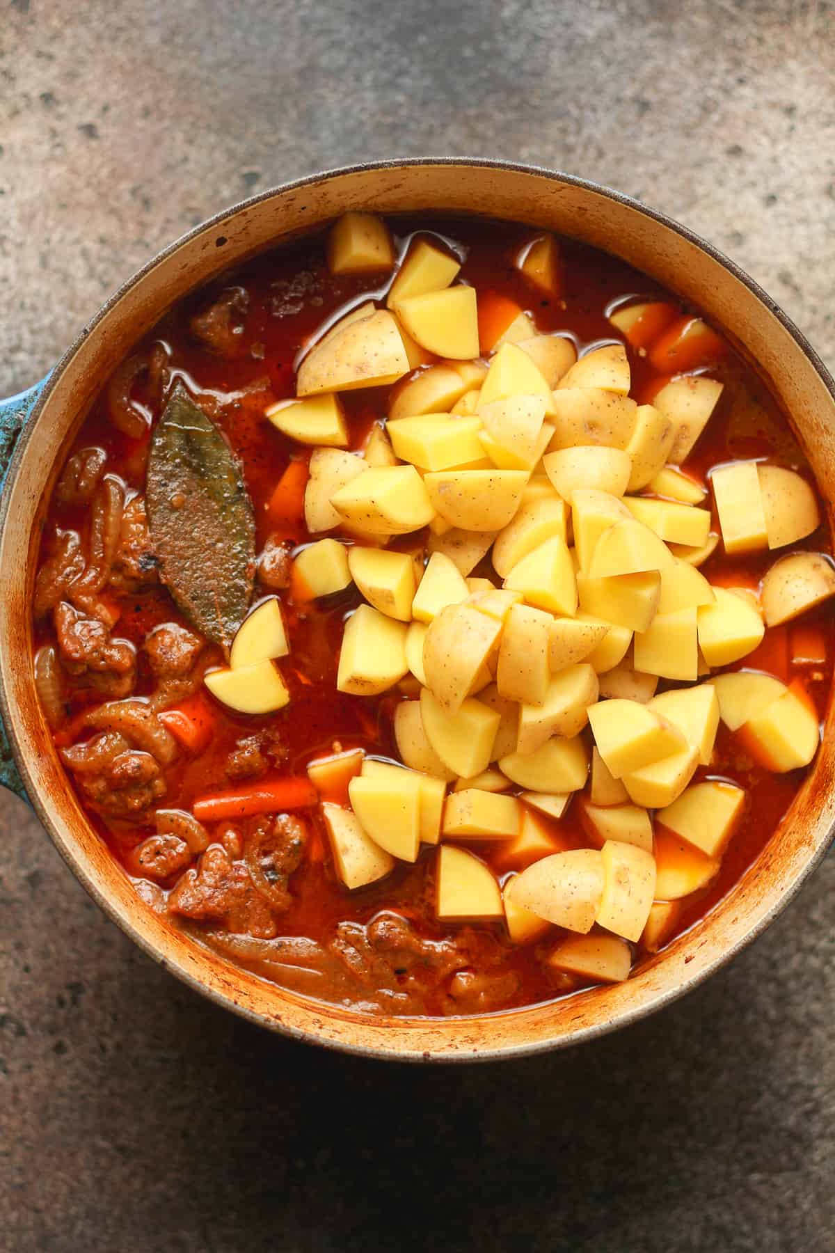 A pot of beef stew with the potatoes on top.