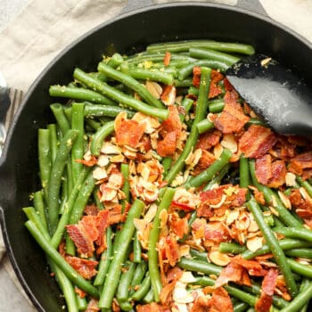 A skillet of green bean almandine with bacon.