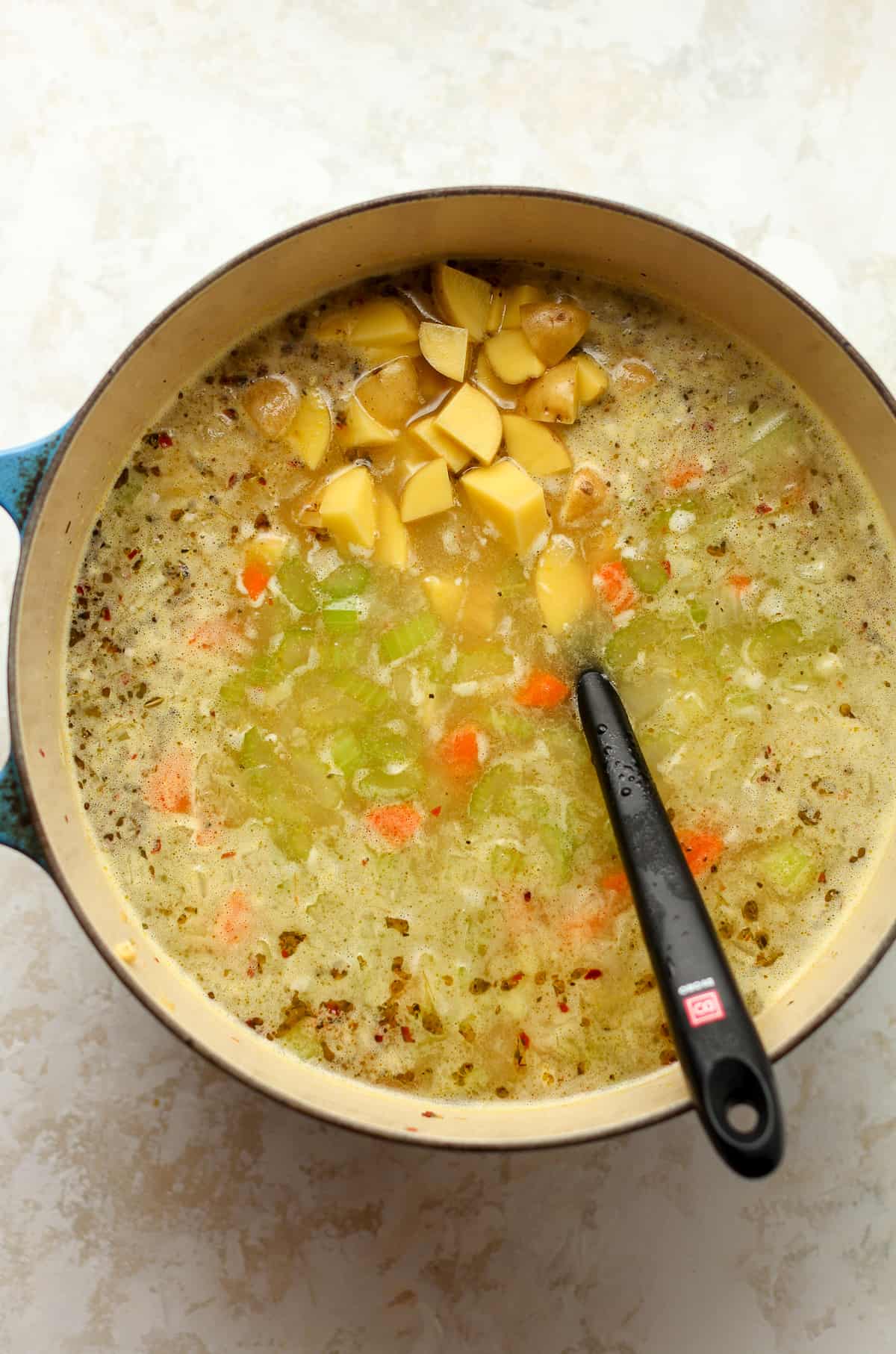 A pot of soup with diced potatoes on top.