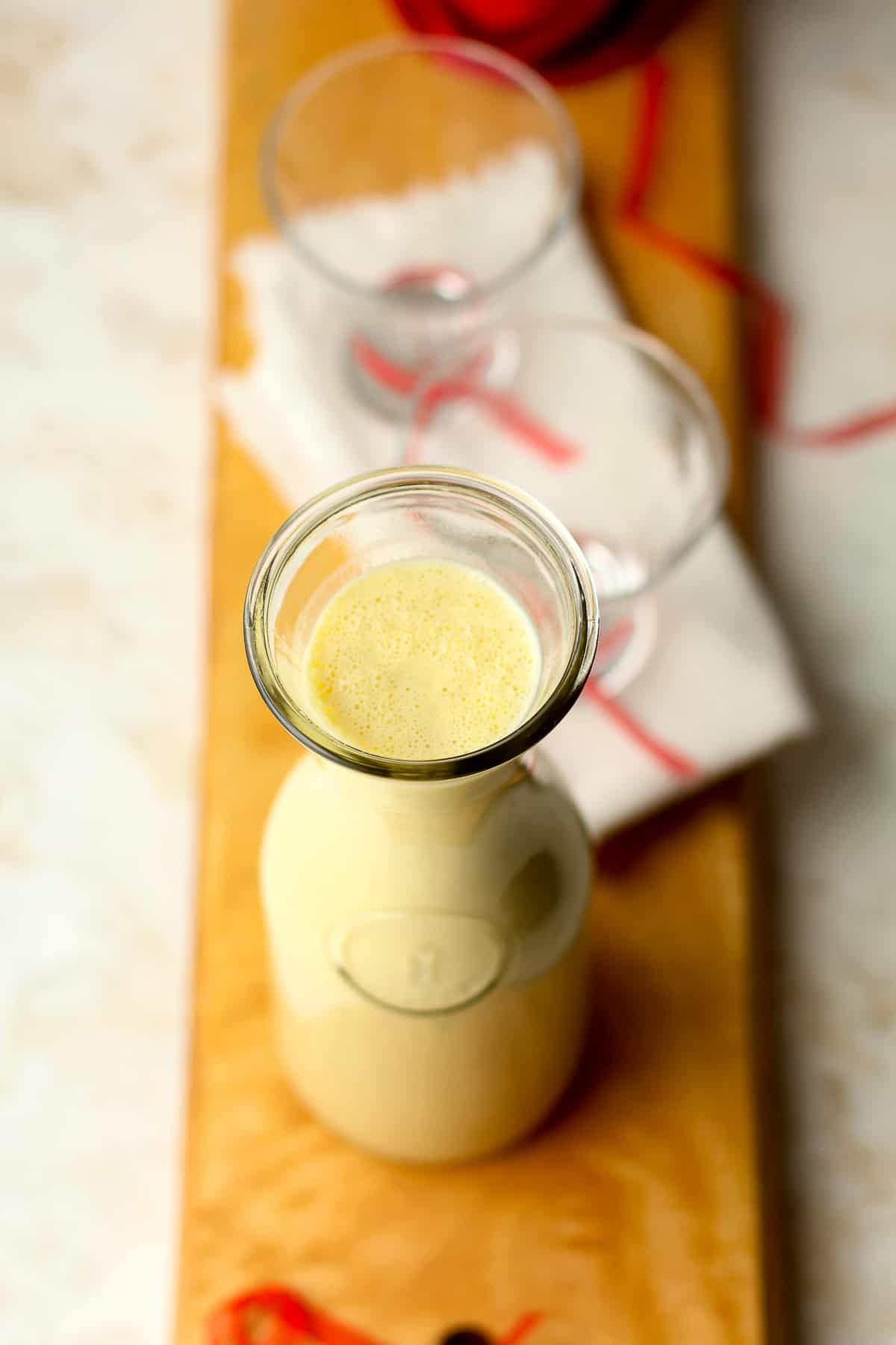 A carafe of homemade eggnog on a wooden board.
