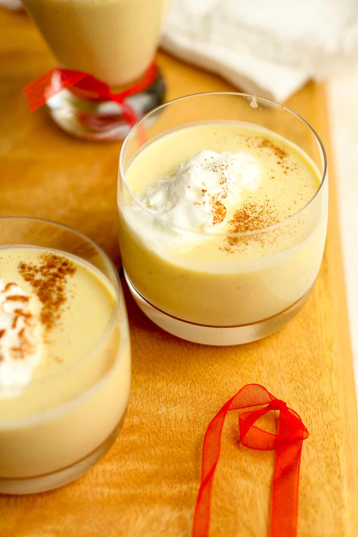 Side view of several glasses of creamy homemade eggnog with cool whip.