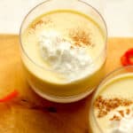 Two glasses of creamy homemade eggnog with whipped cream.