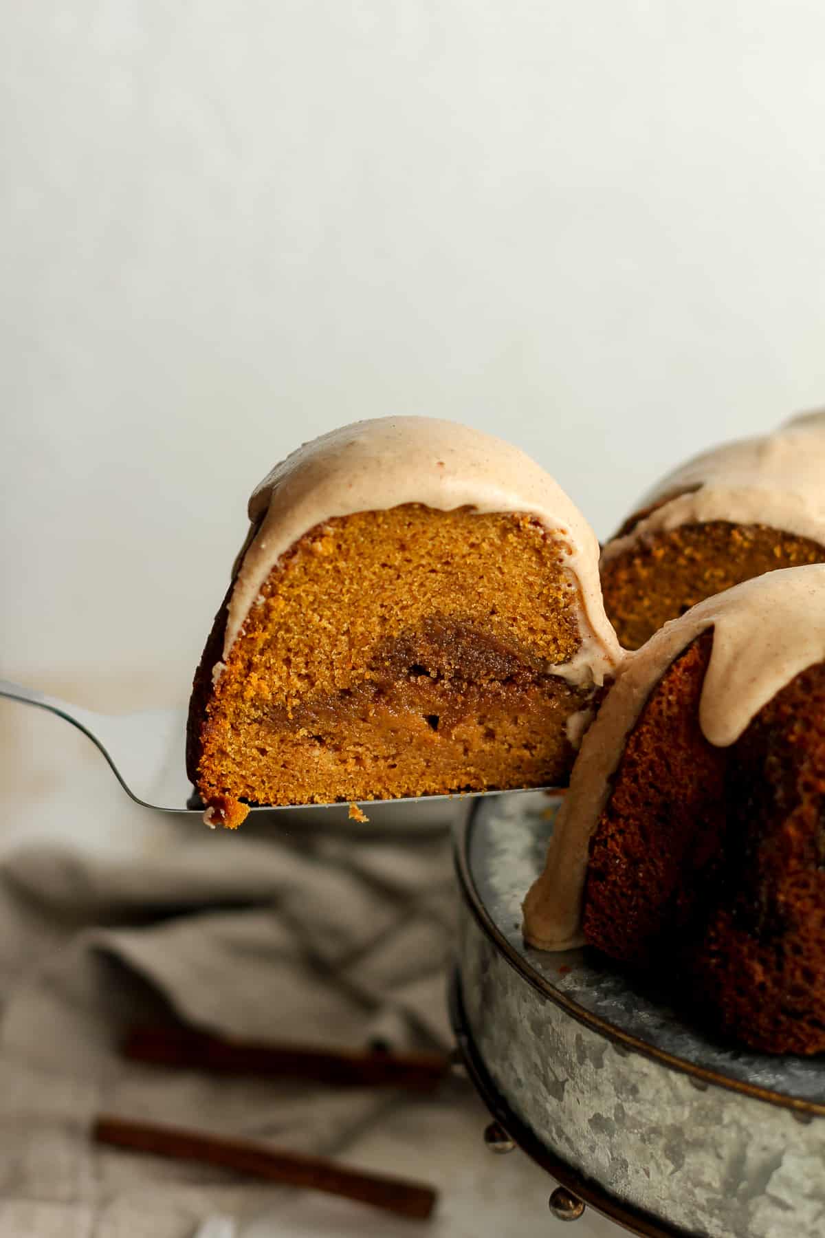 A spatula lifting out a slice of pumpkin bundt cake with cinnamon icing.