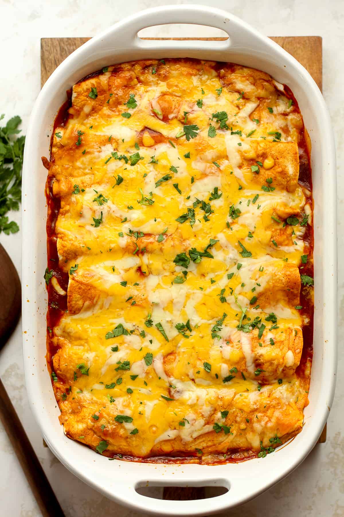 A casserole dish of shredded beef enchiladas with red sauce.