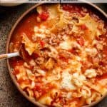 A closeup on a bowl of turkey lasagna soup with cheese.