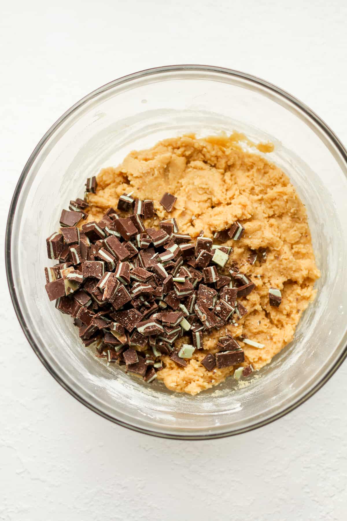 A bowl of the cookie dough with the chopped mints on top.