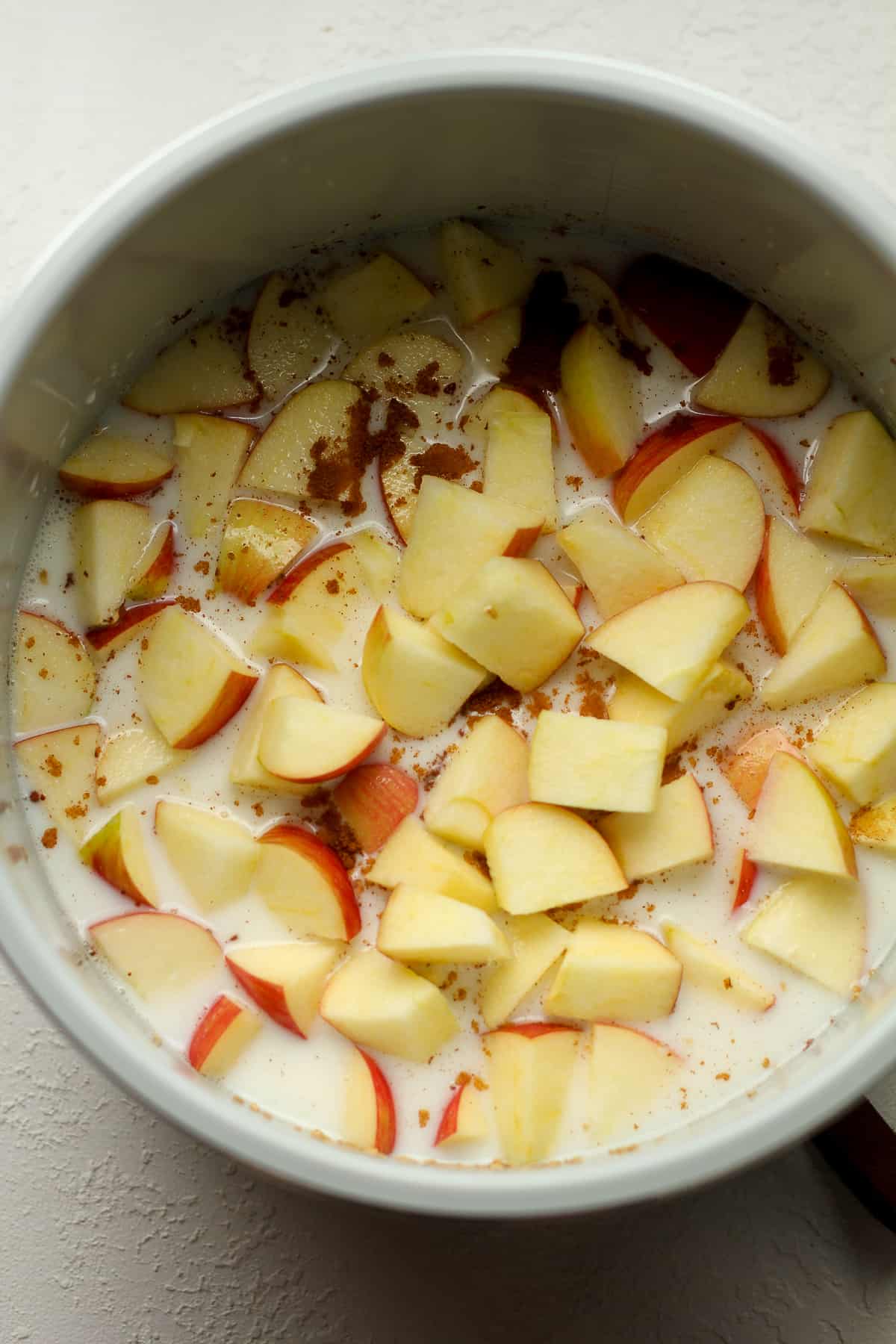 The instant pot after adding the liquids and apples on top of the oats.