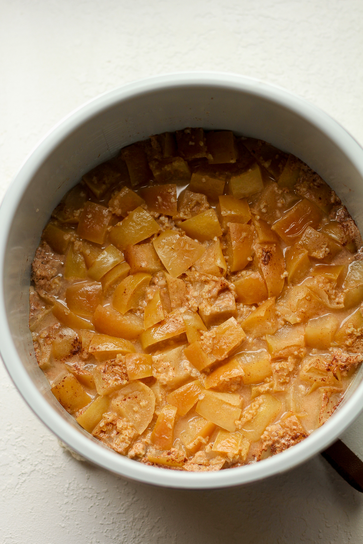 An instant pot of steel cut oats with apple chunks after cooking.