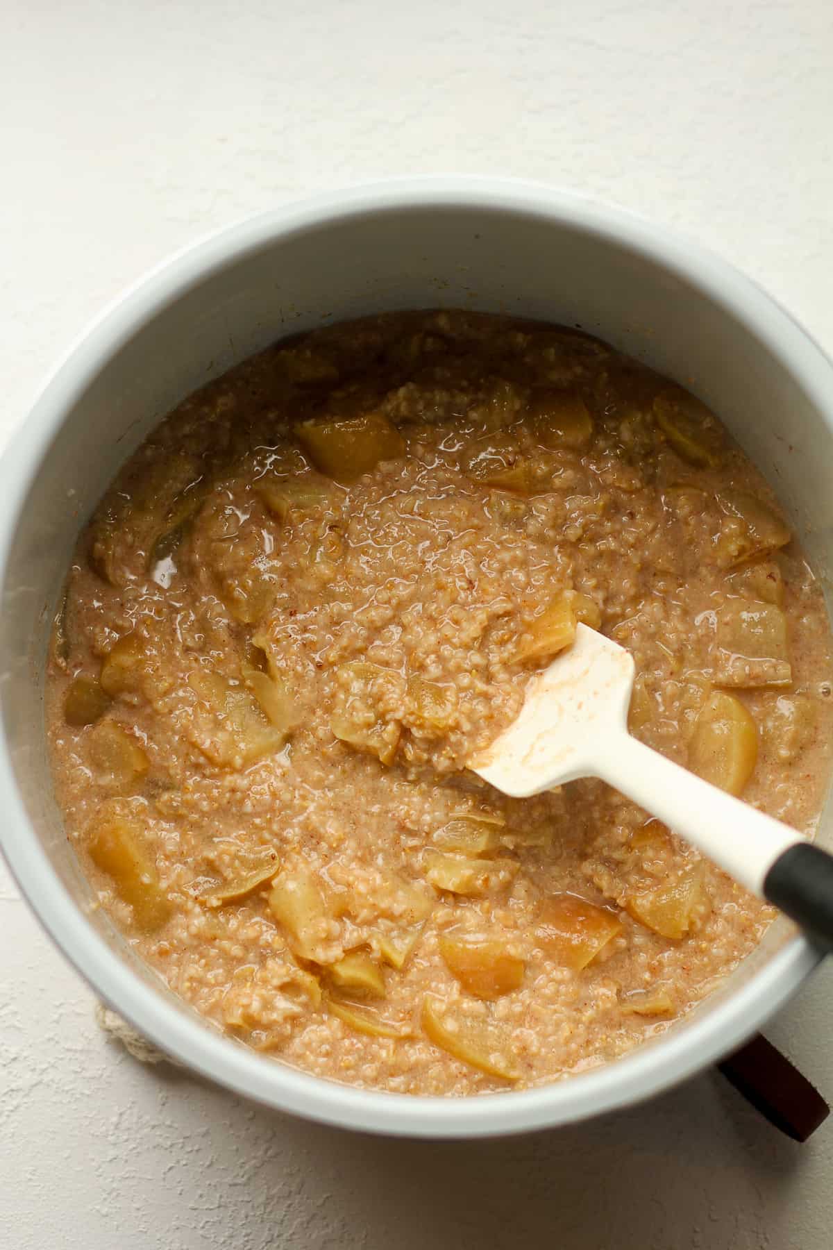 An instant pot of steel cut oats with chunks of apples.