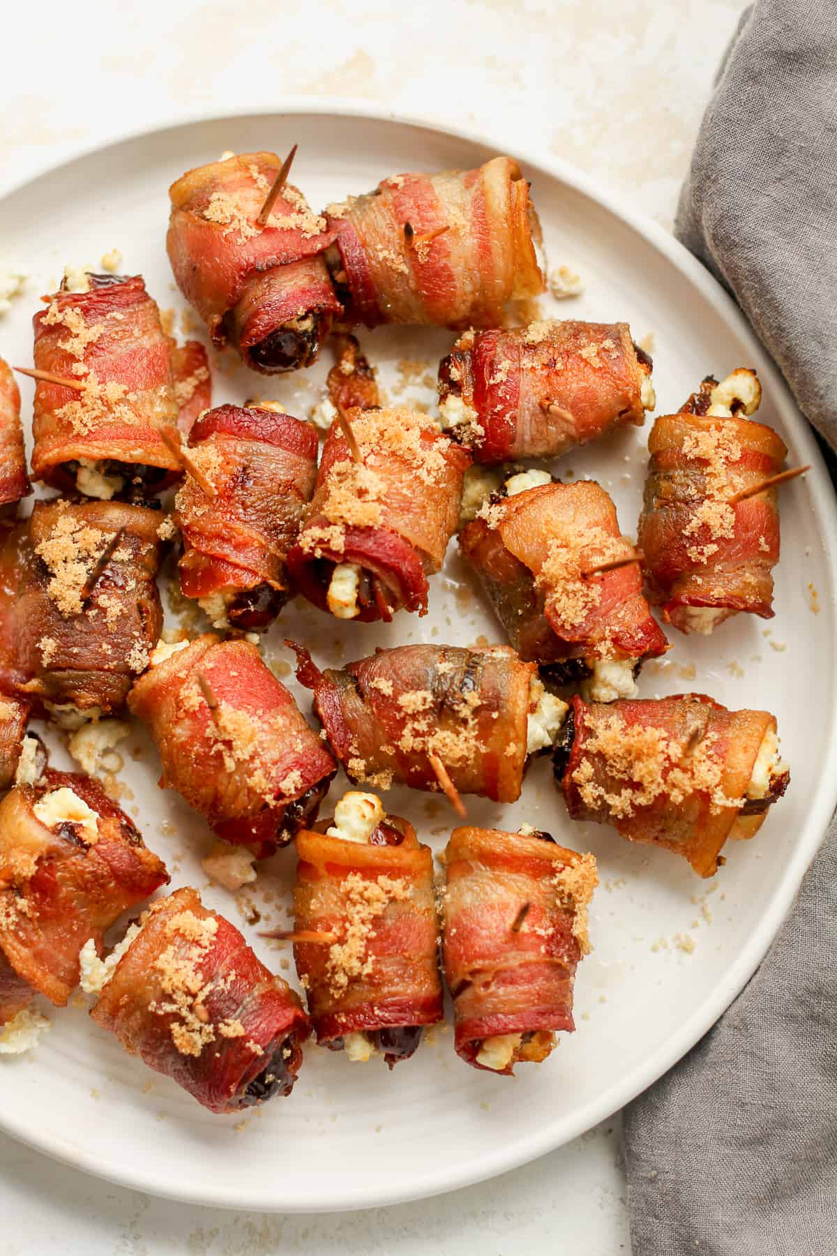 A plate of bacon wrapped dates with toothpicks.