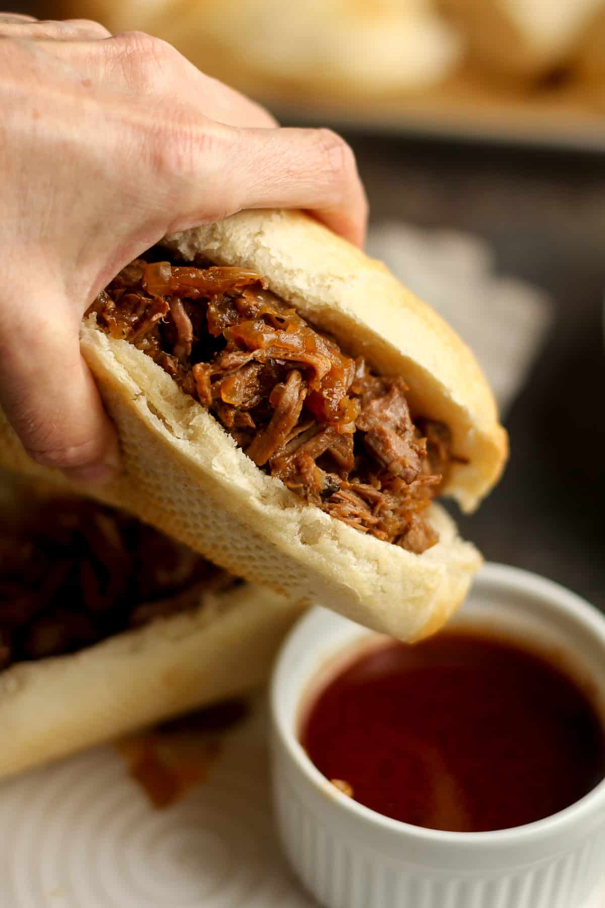 My hand dipping a beef sandwich into the au jus.