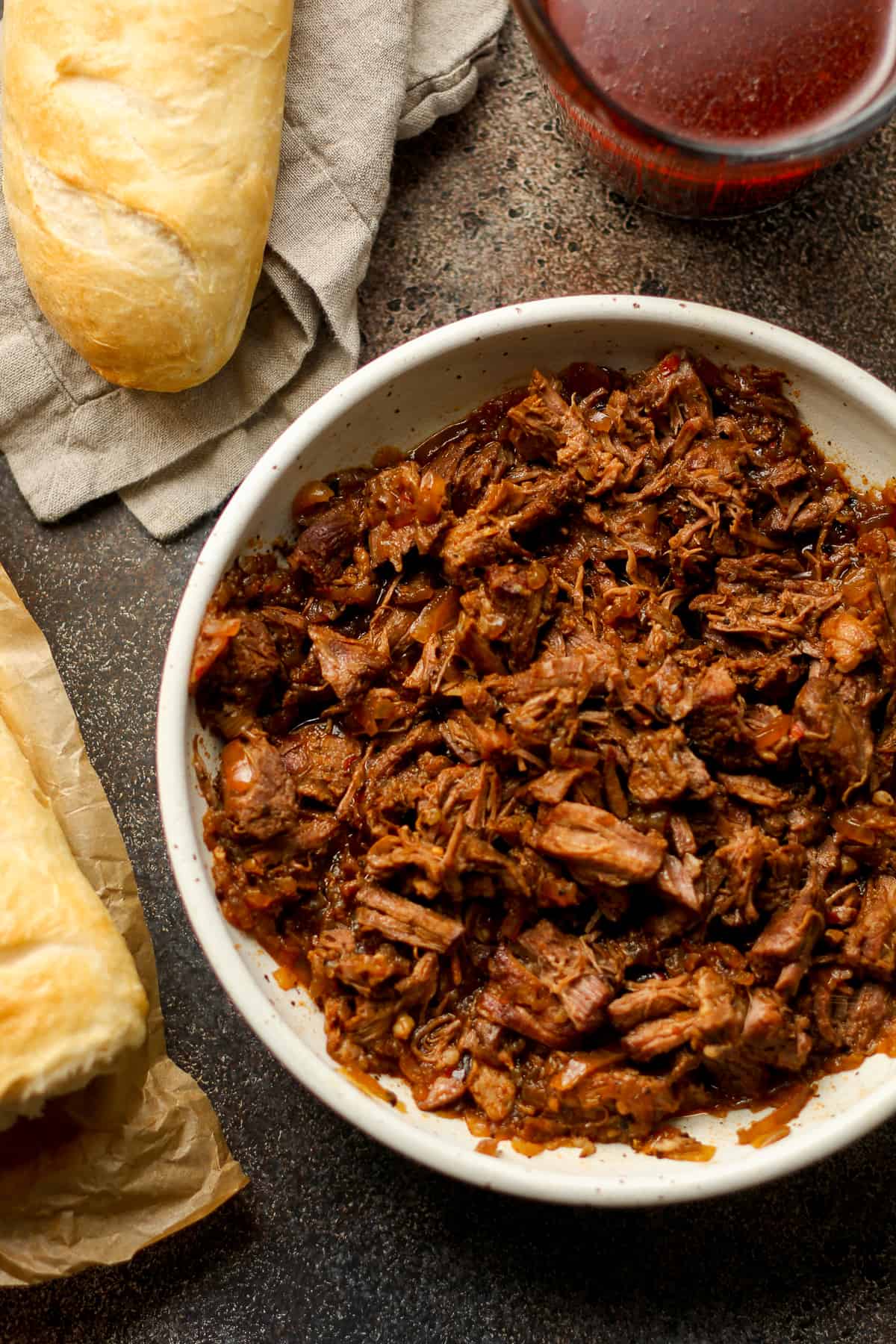 Overhead view of a bowl of beef, with some bread and the au jus.