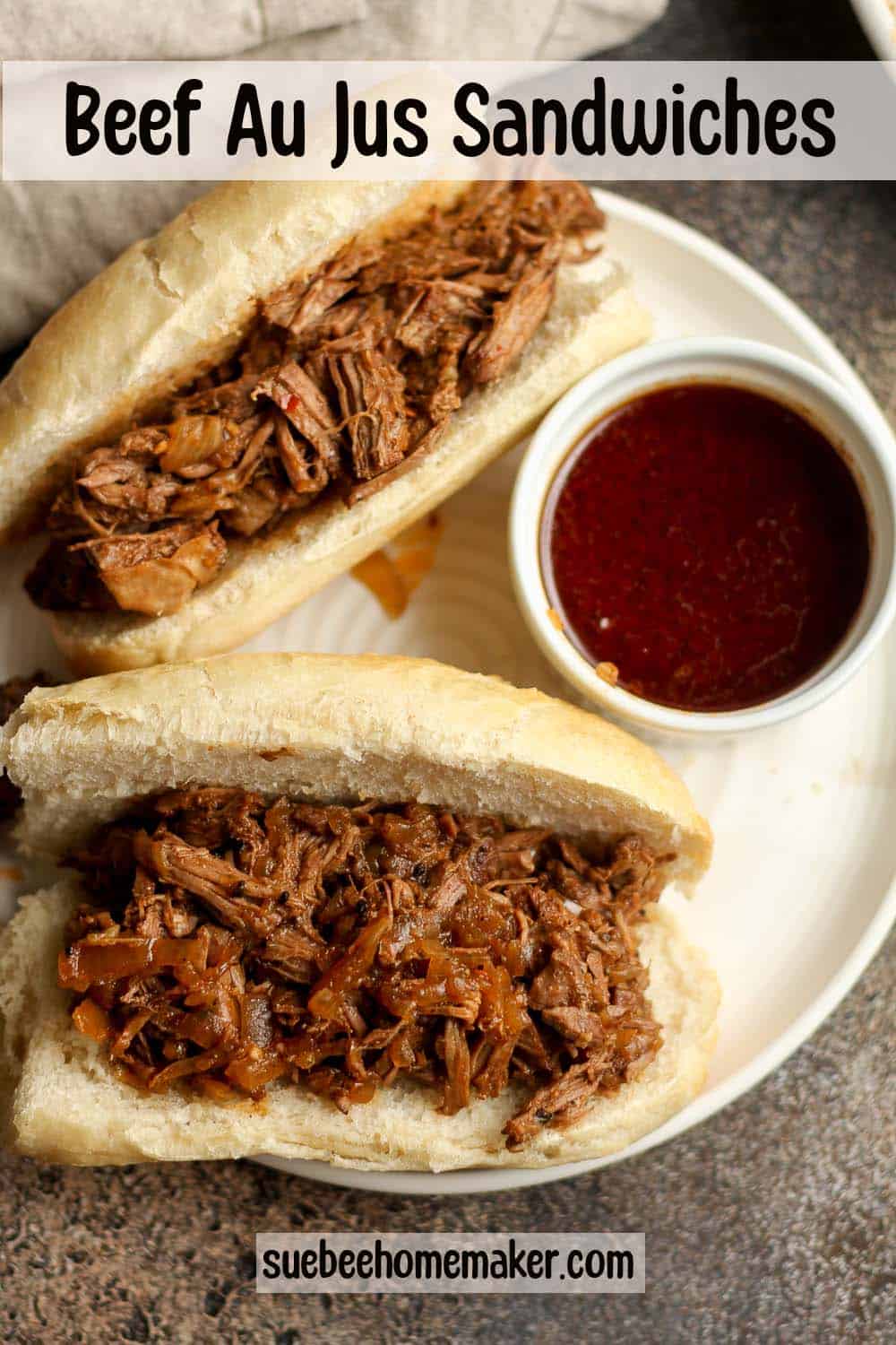 A plate of two beef au jus sandwiches with a side of au jus.