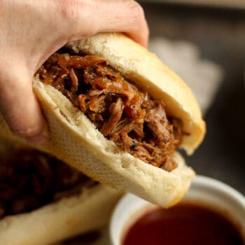 My hand dipping a beef sandwich into au jus.