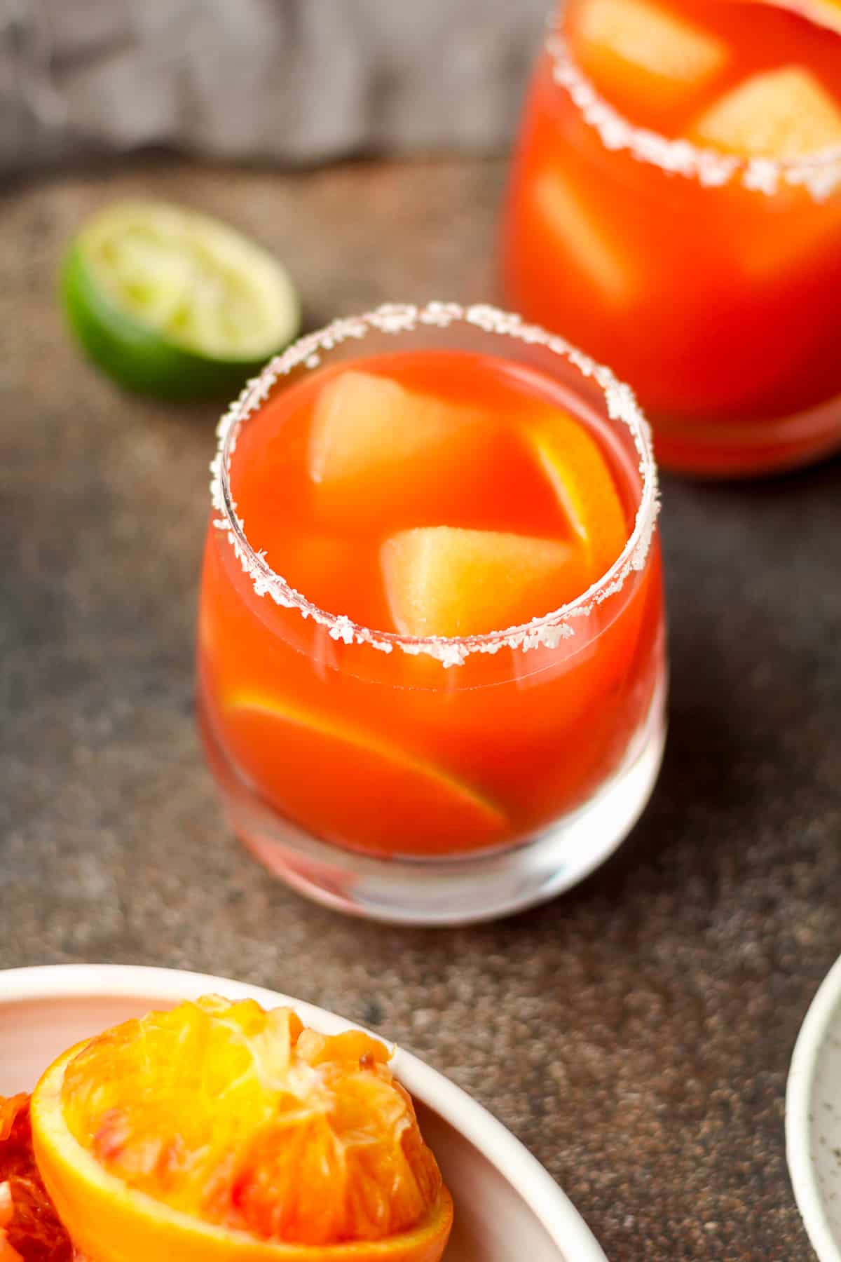 Overhead view of two blood orange margaritas with orange ice cubes.