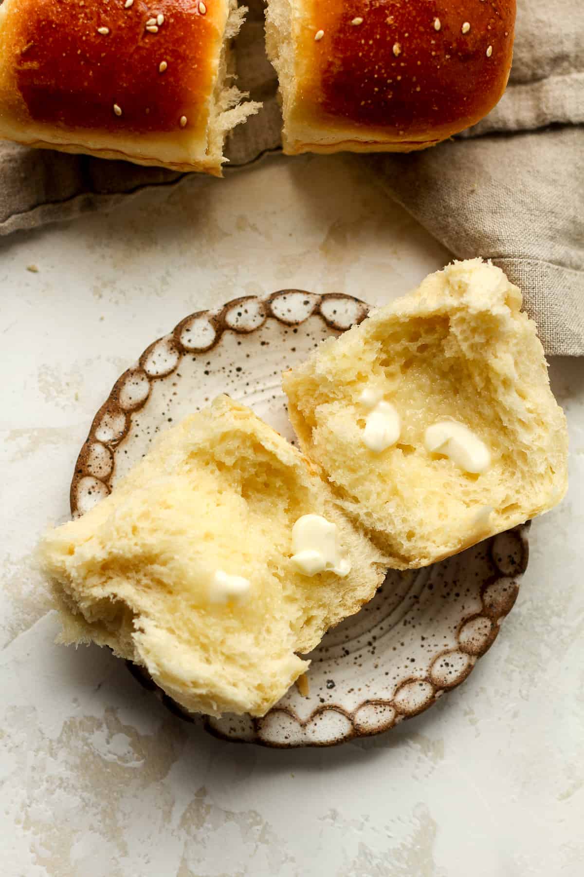 A small plate of a opened brioche dinner roll with butter.