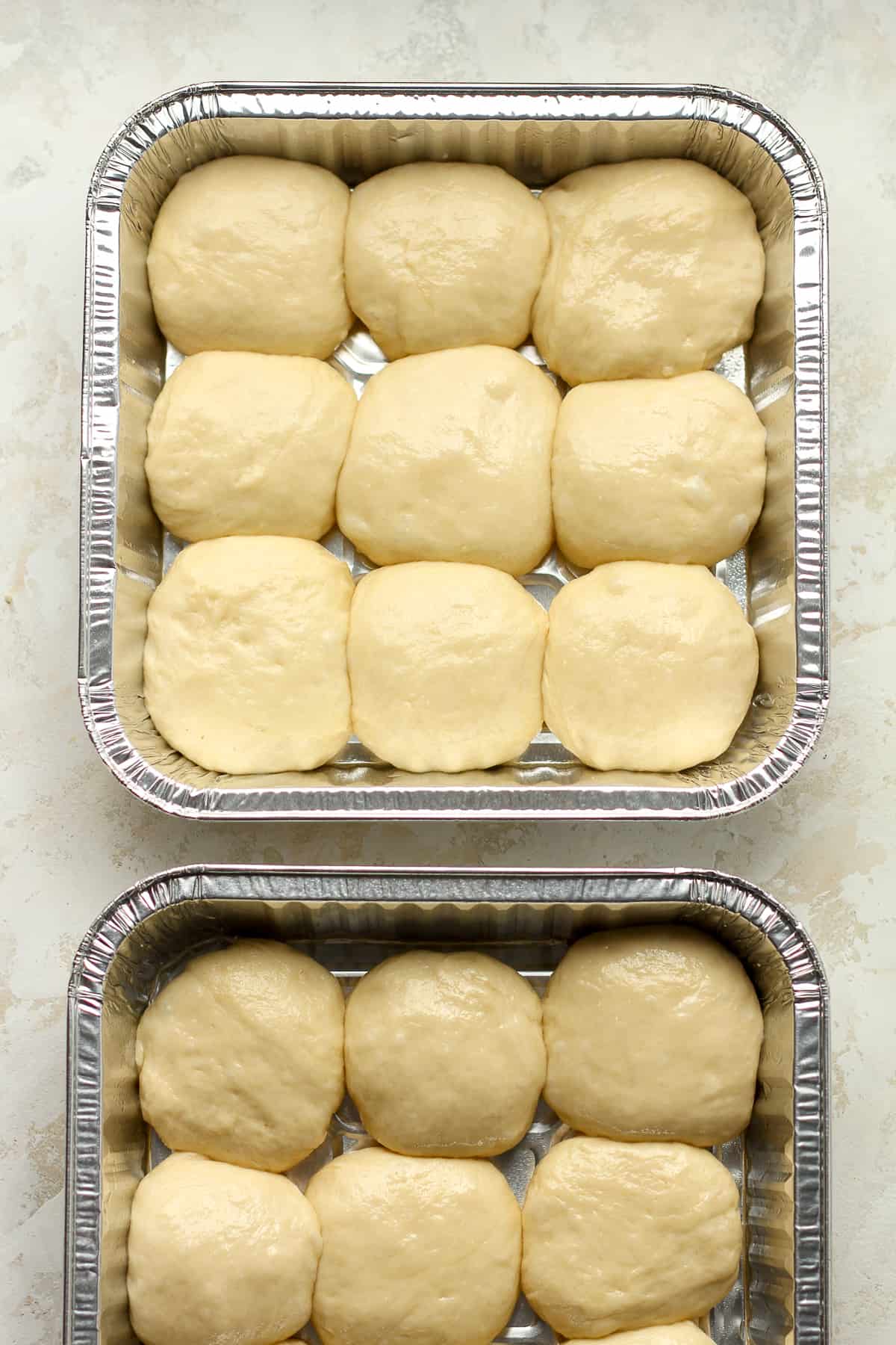 Two pans of brioche dinner rolls after forming.