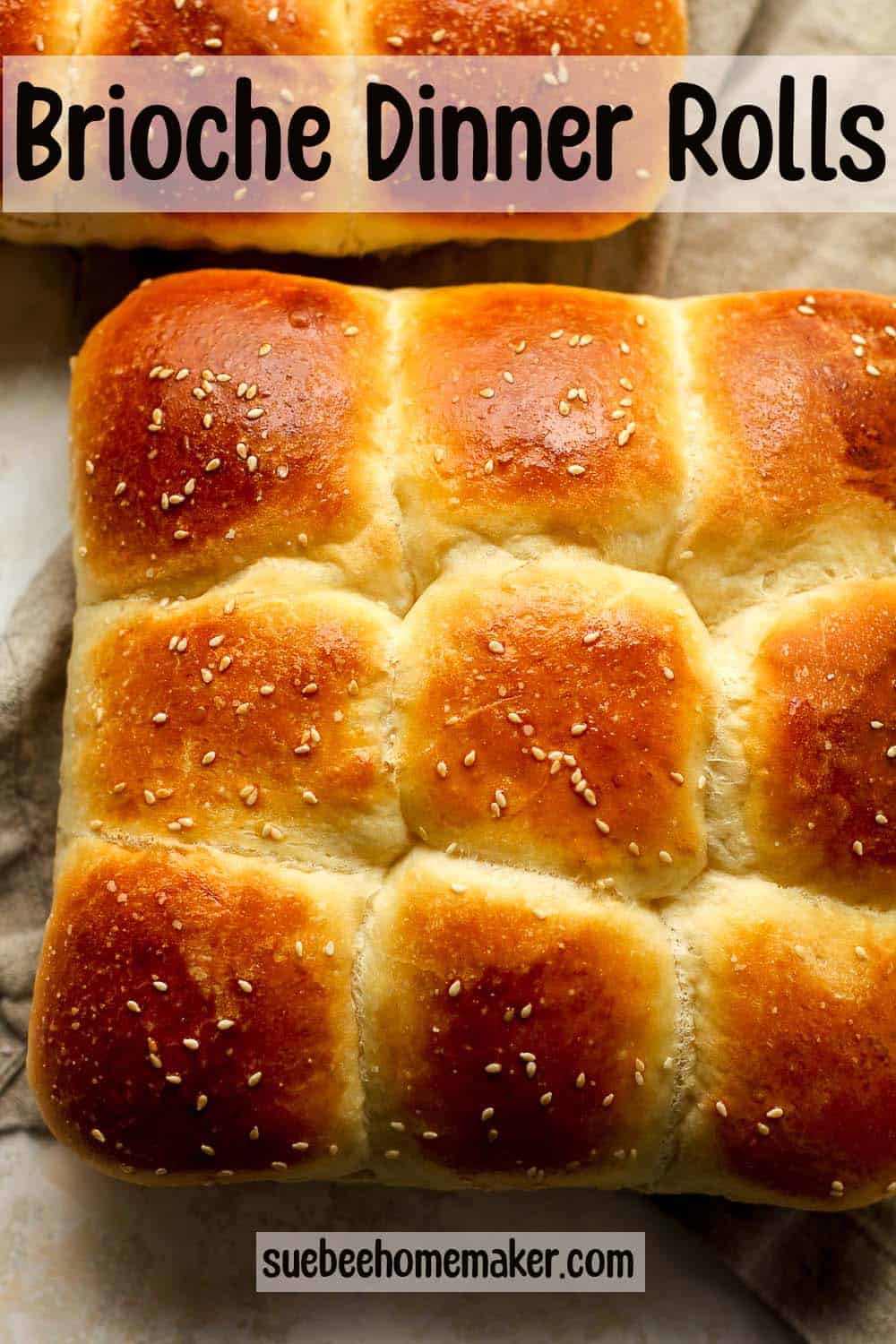 Brioche dinner rolls on a gray napkin.