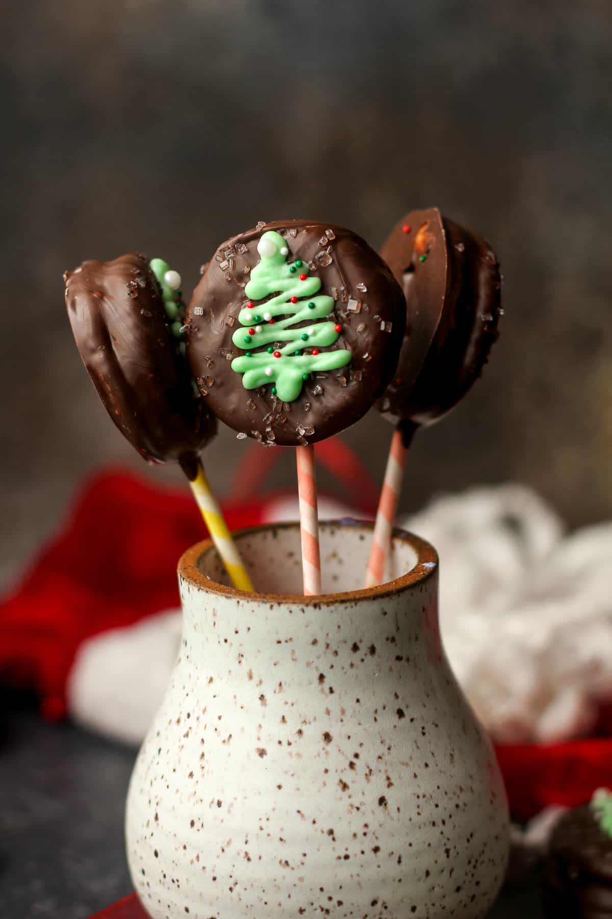 A mug with some Christmas Tree ritz cracker lollipops.