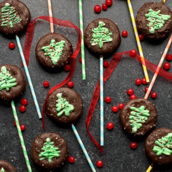 Several chocolate covered peanut butter ritz lollipops on a black background.