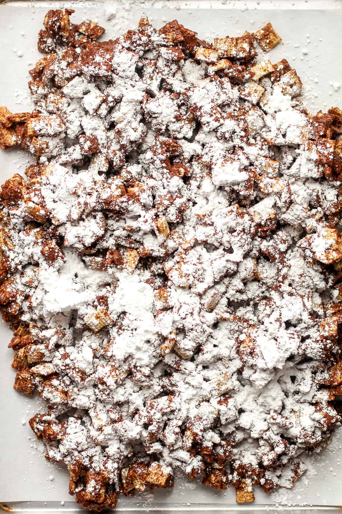 A sheet pan of the Chex mix with the powdered sugar sprinkled on top.