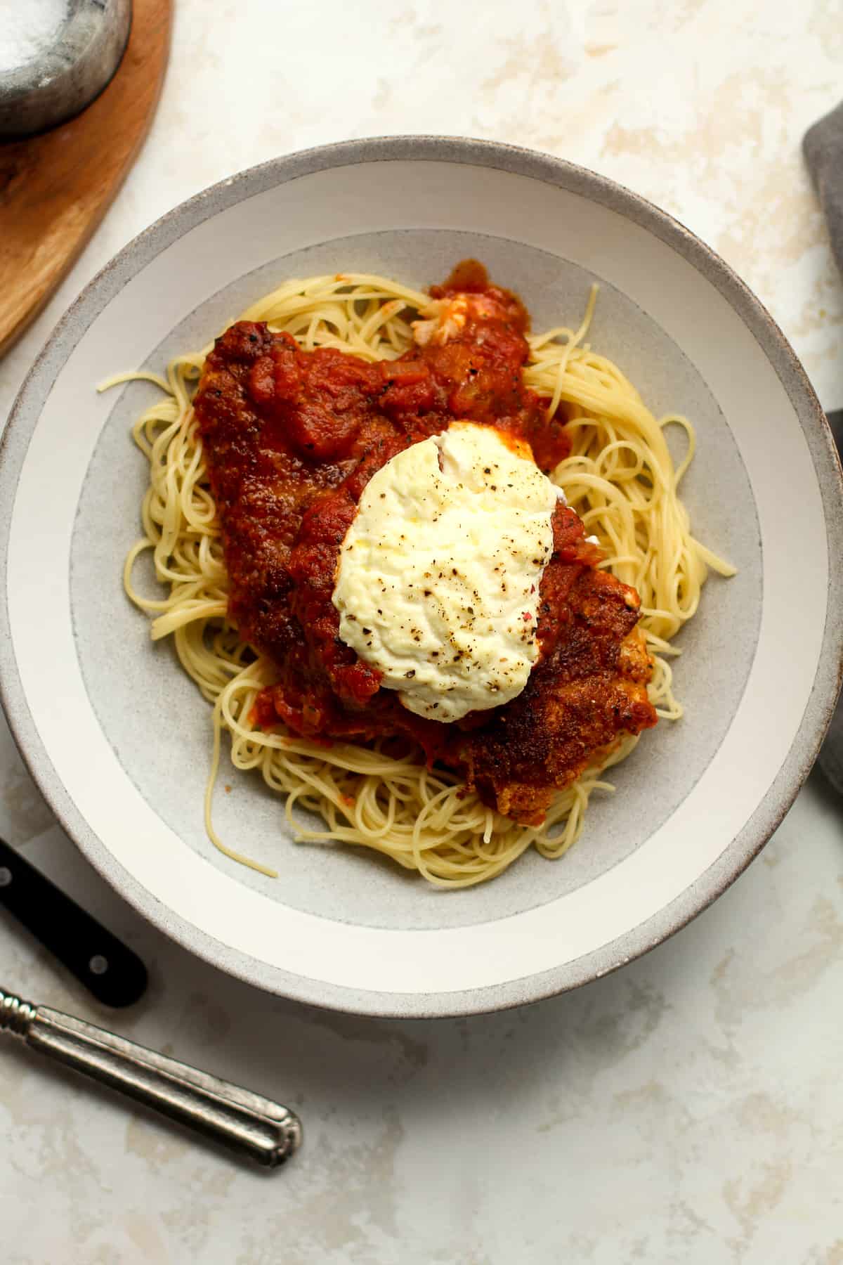 A bowl of pasta with chicken parm on top.