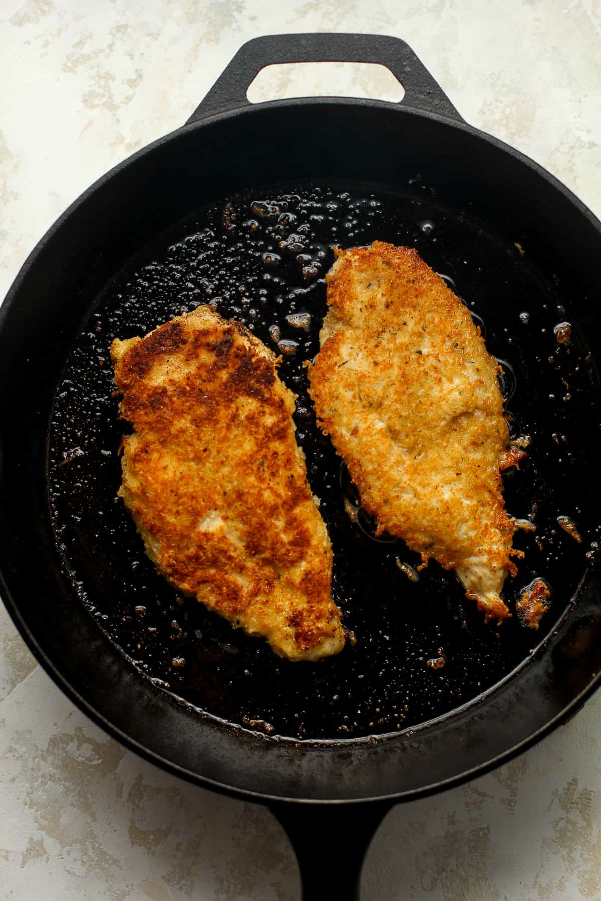 A skillet with two chicken breasts.