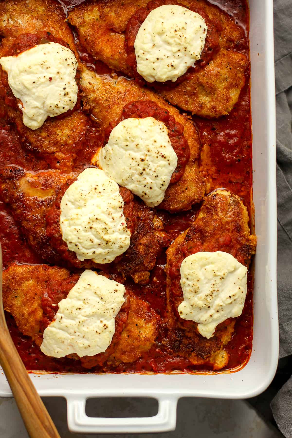Overhead view of a casserole of chicken parm with red sauce.