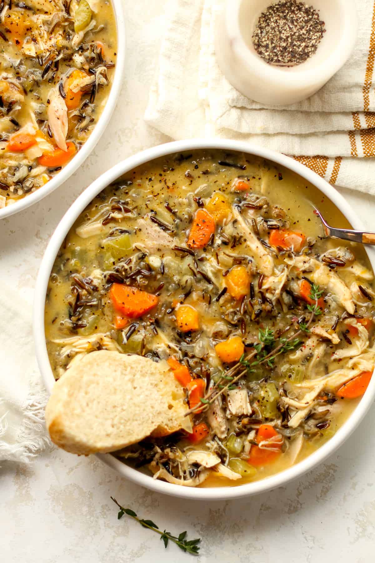 Two bowls of turkey wild rice soup with a slice of bread.